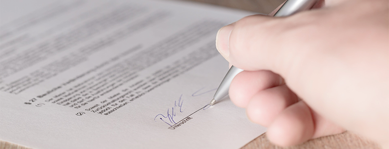 Hand mit Stift ein Dokument unterschreibend